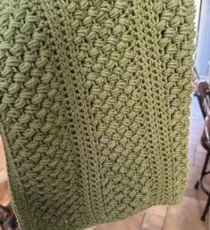 a green crocheted blanket hanging from a hook