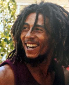 a man with dreadlocks is smiling for the camera