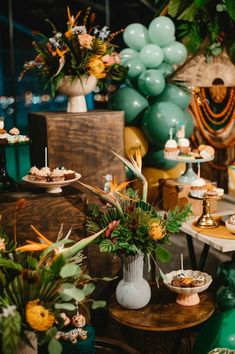 a table topped with lots of desserts next to balloons and flowers on top of it