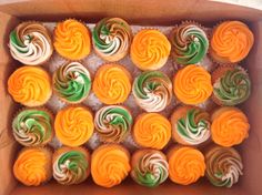 cupcakes with orange, green and white frosting in a box