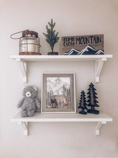 two white shelves with pictures and stuffed animals on them, one is holding a bear