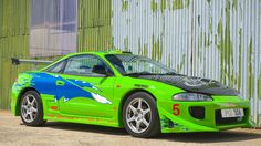 a green sports car parked in front of a building with graffiti on it's side