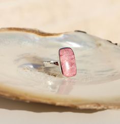 A rectangle cut of the beautiful pink rhodochrosite stone has been set in a sterling silver case sitting perfectly on top of the sterling silver band. This ring is nothing short of groovy and fabulous. The warm, pink tones of the rhodochrosite stone shine through to bring this ring to life.  Available in three sizes; US ring size 8, 9, & 10.  Pair with your choice of rhodochrosite jewellery. Store in a safe place to avoid scratching. Clean carefully with a jewellery cleaning cloth. Rhodochrosite Jewelry, Rectangle Ring, Pink Rhodochrosite, Women Helping Women, Pink Tone, Sterling Silver Bands, Cleaning Jewelry, Silver Band, Semiprecious Stones