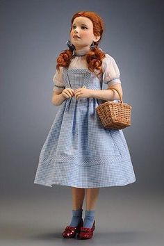 a doll with red hair wearing a blue dress and holding a basket