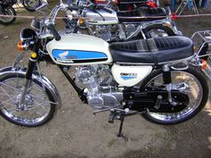 a white and blue motorcycle parked on top of a dirt field next to other motorcycles