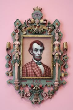 a portrait of abraham lincoln hangs on the wall in an ornately decorated frame against a pink background