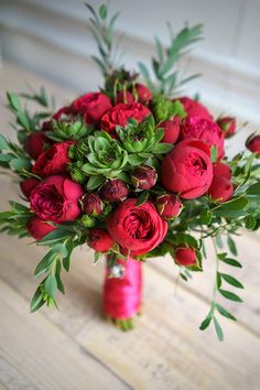 a bouquet of red roses and greenery in a vase