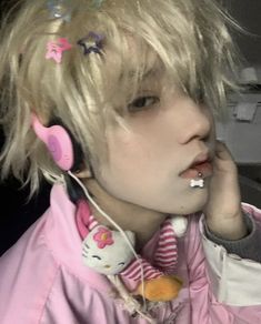 a girl with headphones on talking on her cell phone while wearing hello kitty earbuds