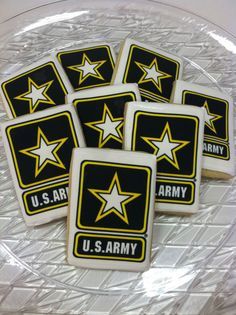 four decorated cookies on a clear plate with the words u s army written in gold