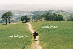 a person walking down a dirt road in the middle of a field