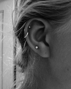 black and white photograph of a woman's ear with two piercings on it