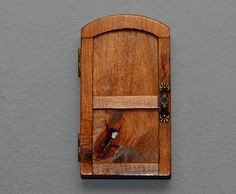 a wooden door on the side of a gray wall with a metal latch in it