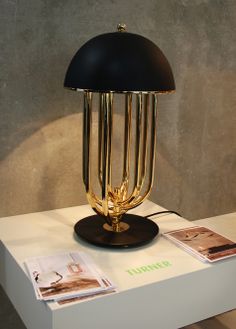 a table with a lamp on top of it next to pictures and magazines in front of a wall