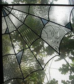 a close up of a stained glass window with trees in the background