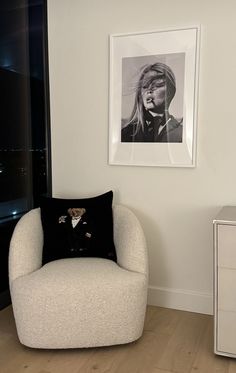 a black and white photo hanging on the wall next to a chair with a pillow