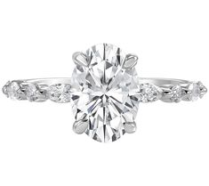 a diamond engagement ring with three stones on the band and an oval cut center stone