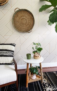 some plants are sitting on a small table in front of a wall with geometric designs