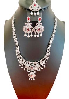 This South Indian Haaram features a stunning peacock design with CZ American Diamonds, making it the perfect accessory for any marriage, party, or as a gift for HER. The medium size is versatile and ideal for pairing with Indian outfits like silk sarees or gowns. Expertly crafted for an elegant touch. This jewellery set includes a necklace, matching earrings and a maang tika. Jewellery Care- Keep the jewellery dry, avoid contact with perfumes and water. Elegant Silver Sets For Eid, Elegant Silver Sets For Diwali, Elegant Hand Set For Diwali, Elegant Bridal Sets For Eid Festivities, Traditional Formal American Diamond Sets, Elegant Festive Sets With American Diamond, Traditional American Diamond Bridal Sets For Party, Elegant Bridal Sets With Tilla Detailing, Temple Jewelry Sets With Peacock Design For Weddings