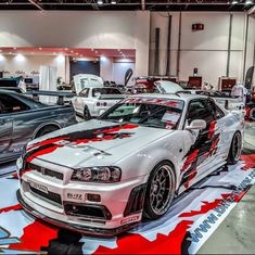 several cars are on display in a showroom with red, white and black paint