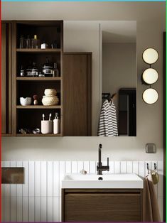 a bathroom sink sitting under a mirror next to a wooden cabinet