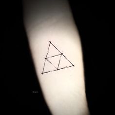 a small triangle tattoo on the left inner arm, with an arrow drawn in it