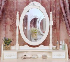 there is a white vanity with a mirror and flowers on the shelf next to it