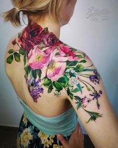 a woman with flowers on her back shoulder and chest tattooing it's upper half