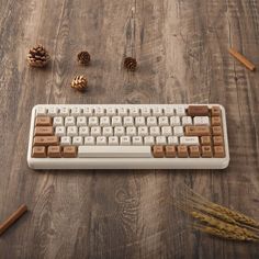 a computer keyboard sitting on top of a wooden table next to pine cones and cinnamon sticks