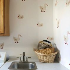 a basket sitting on top of a kitchen counter next to a wall with ducks painted on it