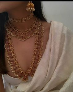 a woman wearing gold necklaces and matching jewelry with her white shawl in the background