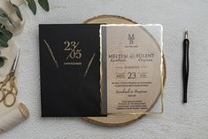 a black and gold wedding suite on a wooden plate with scissors, pen and greenery