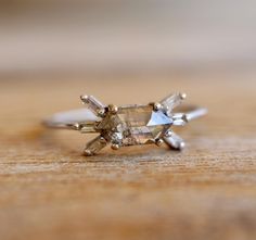 a close up view of a diamond ring on a wooden surface