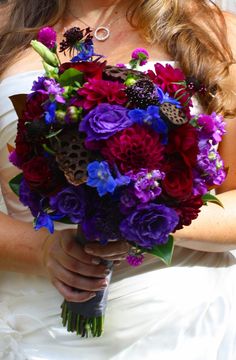 a woman holding a bouquet of purple and red flowers