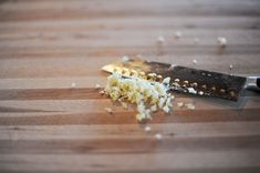 chopped onions on a wooden cutting board with a knife next to it and some garlic flakes