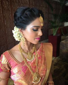 a woman in a pink and gold saree with jewelry on her neck, looking off to the side