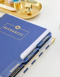 a stack of blue notebooks sitting on top of a white table next to a pen