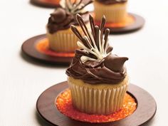 four cupcakes with chocolate frosting and sprinkles on small plates