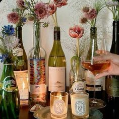 a person holding a wine glass in front of several bottles and glasses on a table