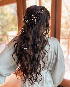 the back of a woman's head with long hair and flowers in her hair