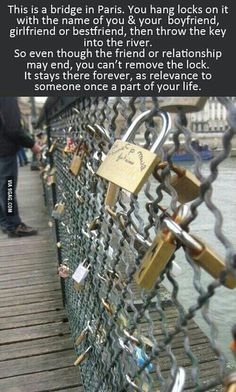 several padlocks attached to a chain link fence with water in the back ground