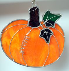 a stained glass pumpkin ornament hanging from a chain