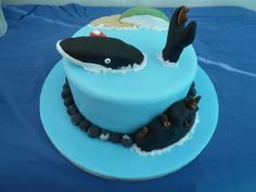 a blue cake decorated with an orca whale and other marine creatures on it's side