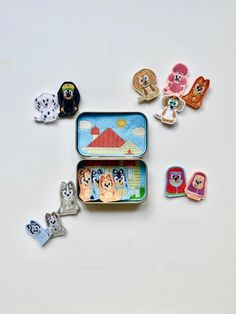 an open tin with various animal magnets in it on a white surface next to each other