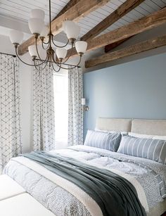 a large bed sitting under a window next to a wooden ceiling fan and light fixture