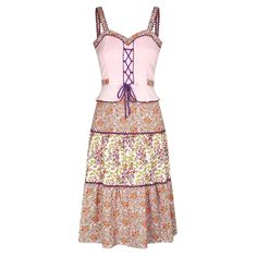 This is a really good example of late 60s to early 70s fashion when the hippie vibe was in full swing in America. This is most likely a European equivalent, on account of the dress looking very alpine style. This design has an integral bodice which is made to look like it is separate from the skirt. The corset ties are to some degree adjustable if a more fitted look is desired. The skirt fabric is cotton, and the bodice is more of a muslin which looks like it has been heat treated to provide an interesting, textured look. The sweetheart neckline is edged in a purple ric-rac trim which also edges the arm straps and separates the three floral tiers on the A-line skirt. The dress has a belt that is sewn into the two front panels and reaches round the hip to tie at the back. The original centr Early 70s Fashion, 1960s Cocktail Dress, 70s Mode, Peach Maxi Dresses, 1950s Cocktail Dress, 1970 Dress, Classic Sheath Dress, New Look Fashion, Alpine Style