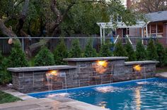 an outdoor swimming pool with lights on the side