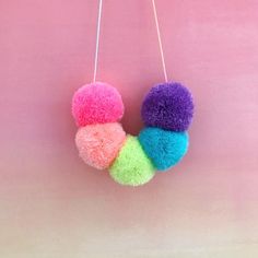 three pom - poms hanging on a pink wall