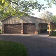 two garages in the middle of a driveway with trees and grass on either side