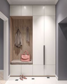 a white closet with two coats hanging on the wall and a pink purse in front