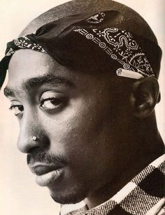 a black and white photo of a man with a bandana on his head looking to the side